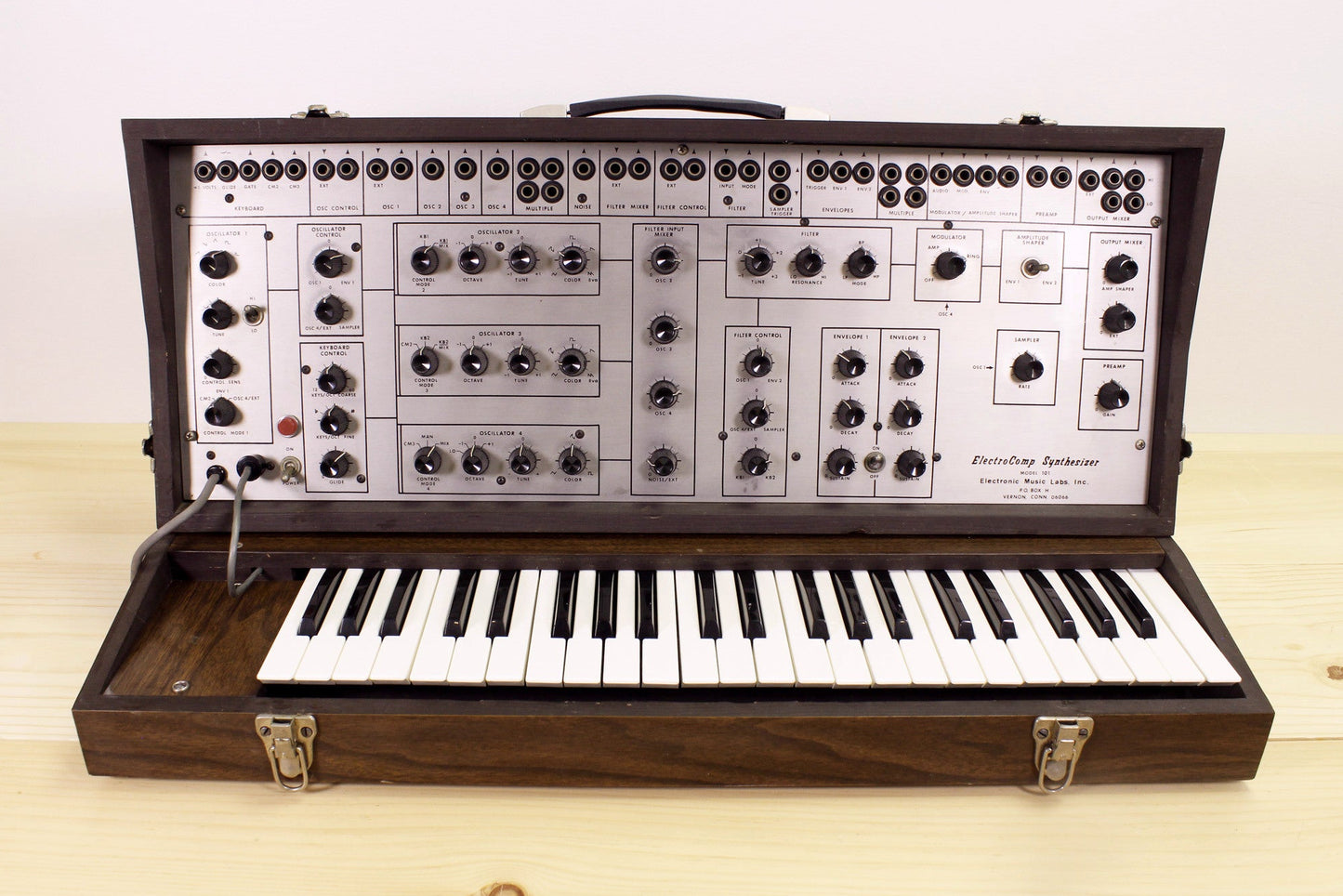 Vintage EML-101 semi-modular synthesizer with wooden casing on a light background