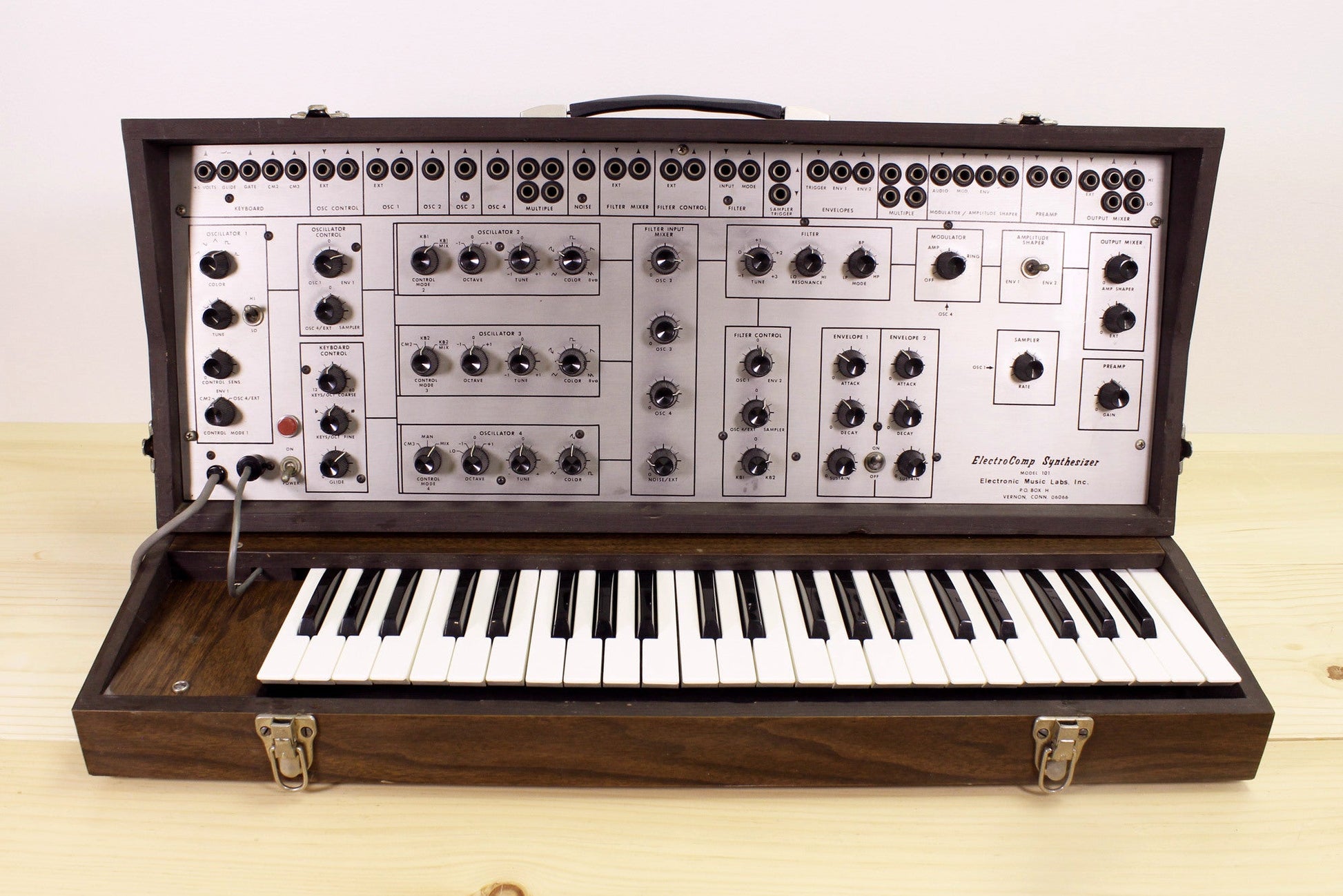 Vintage EML-101 semi-modular synthesizer with wooden casing on a light background